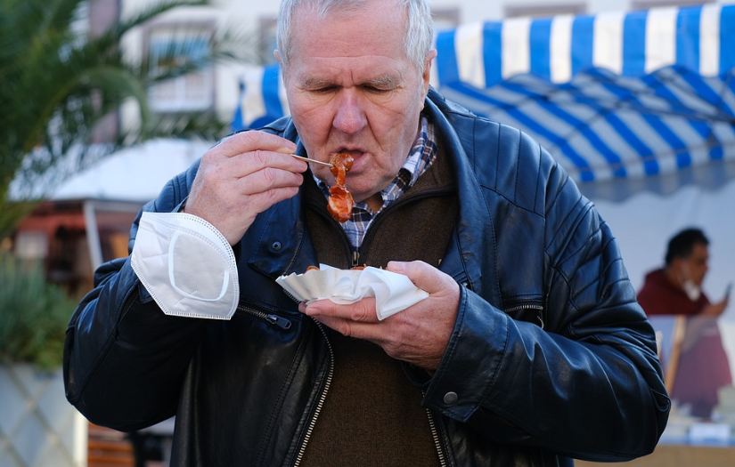 An overweight man eating junk food