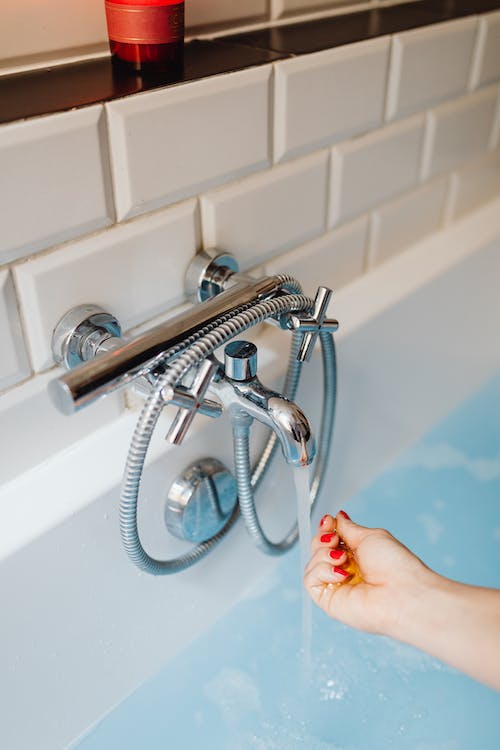 a person checking the temperature of the water from a faucet