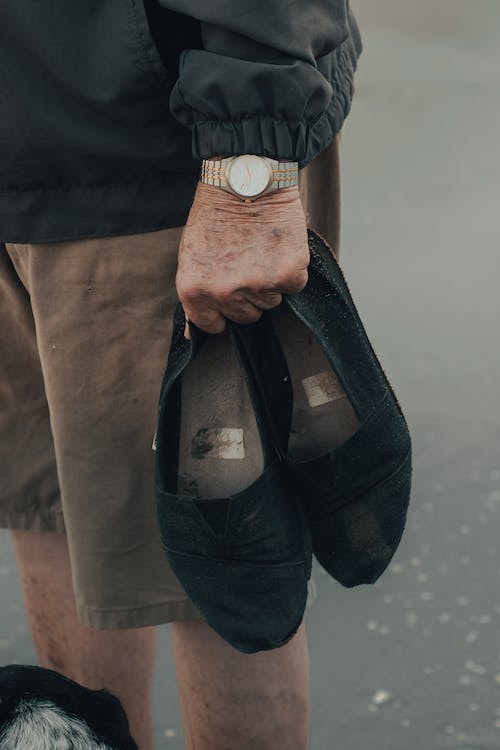 an old man holding a pair of black shoes