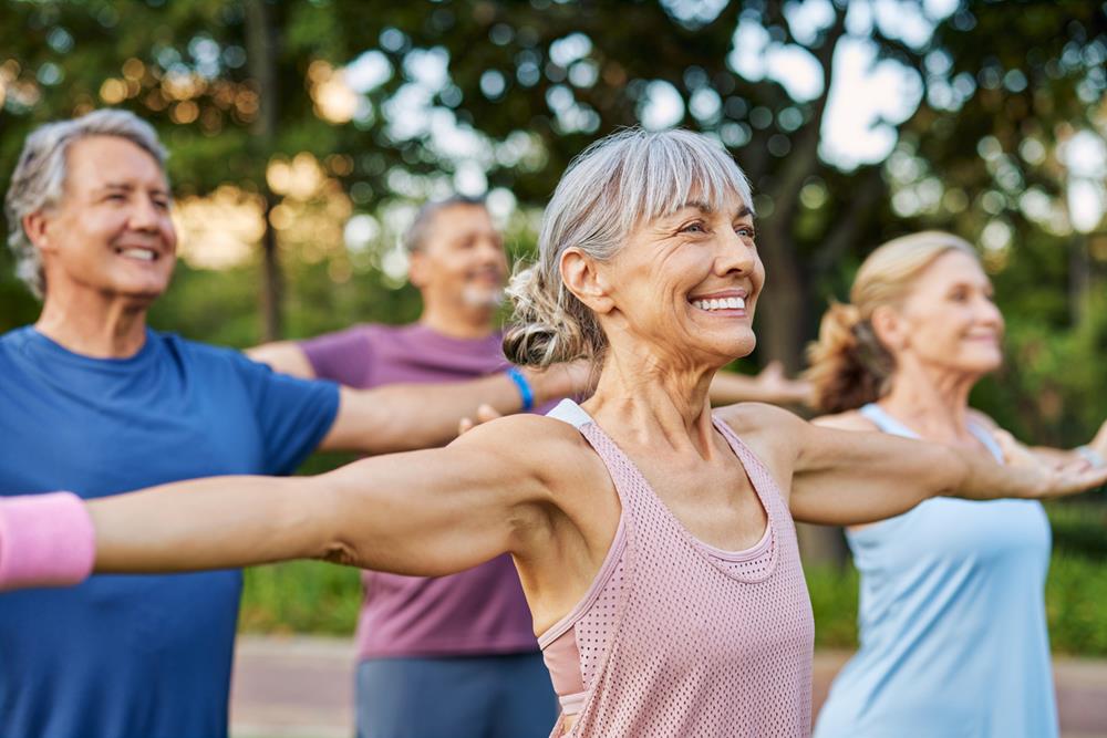 Happy senior group doing yoga together in the park